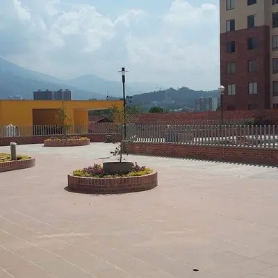 Plaza común exterior con jardineras circulares de ladrillo.